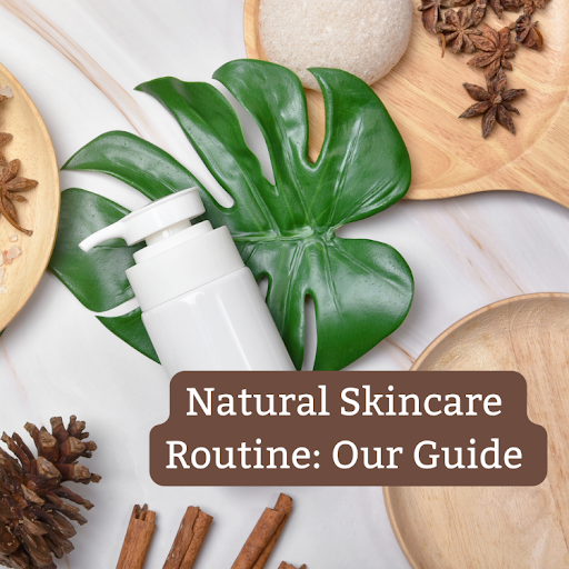  A flat lay image showcasing a natural skincare theme. There is a white dispenser bottle with a pump lying on a green monstera leaf. Surrounding the bottle are wooden bowls, a natural sponge, pine cones & cinnamon sticks.
