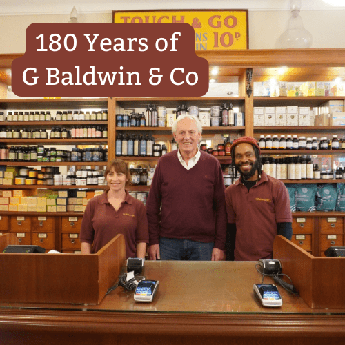Baldwins CEO Steve Dagnell stood behind a wooden store counter with two staff members.