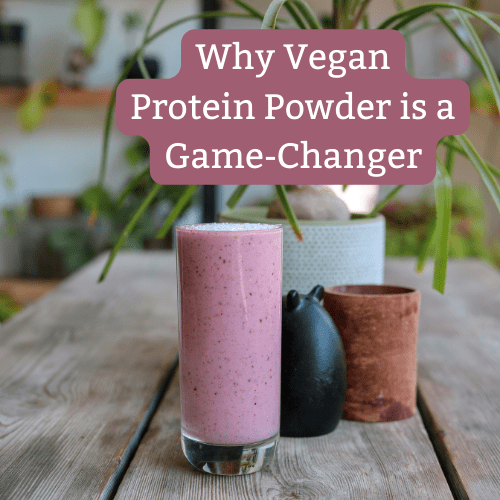 Glass of pink vegan protein smoothie on a wooden table with text overlay 'Why Vegan Protein Powder is a Game-Changer'.