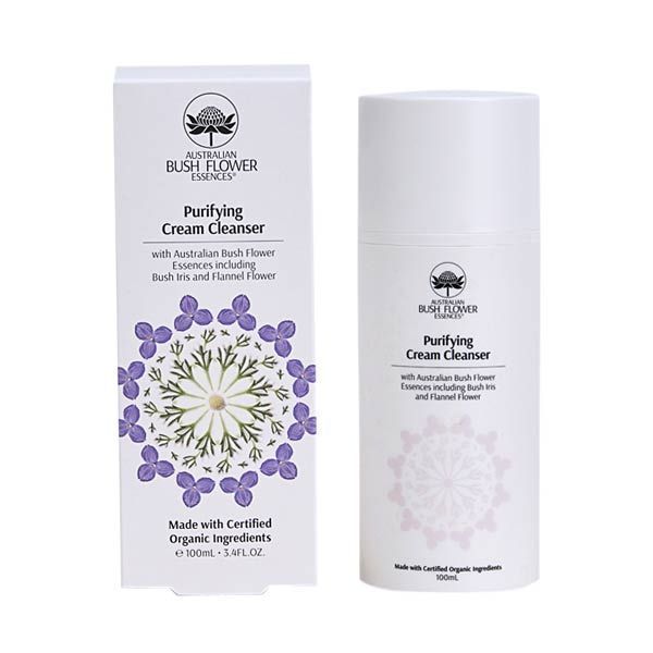  A white tube and its corresponding box for "AUSTRALIAN BUSH FLOWER ESSENCES Purifying Cream Cleanser". The packaging is adorned with purple and white floral graphics and states it contains Australian Bush Flower Essences including Bush Iris and Flannel Flower. It is labelled as made with certified organic ingredients and is 100ml in volume. The background is solid white, highlighting the product.