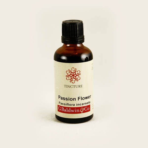 A small amber glass bottle with a white label for "Passion Flower Tincture" (Passiflora incarnata) from G Baldwin & Co. The label features a decorative red motif above the product name. The bottle cap is black, and the simple design indicates a herbal remedy product.