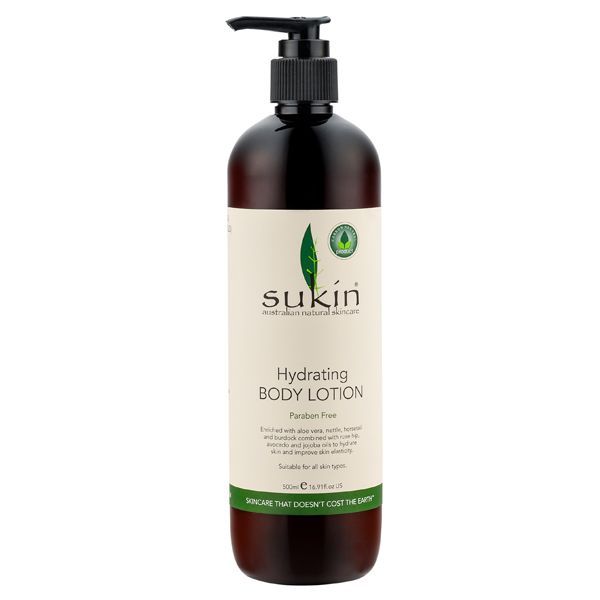  A large amber plastic bottle with a black pump dispenser, labelled "Sukin Hydrating Body Lotion," paraben-free and suitable for all skin types, in a 500ml volume. The bottle has a cream and green label with a leaf emblem, set against a white background.