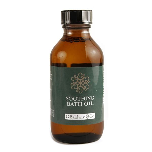  An amber glass bottle with a metal cap, labelled "G. Baldwin & Co Soothing Bath Oil". The label has an ornate design and is in shades of green and white, all set against a plain background for clarity.